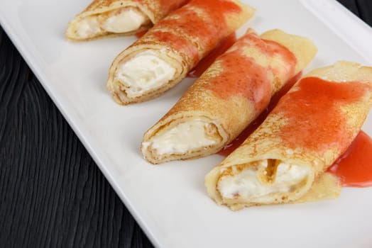 Pancakes or russian blini stuffed with cream sauce on a white plate.