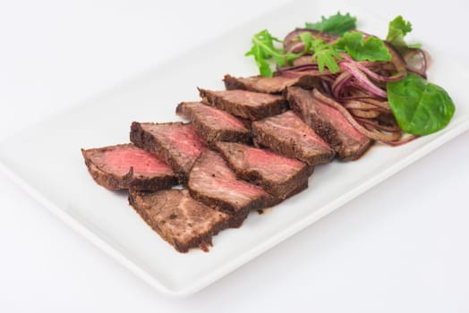 Plate with meat cutting and fresh greens on white plate