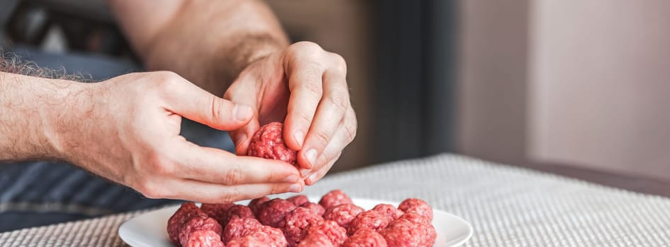 Man hands preparing meatballs with raw mincemeat. Lifestyle close up composition with natural light. Homemade cooking during lockdown, stay home housekeeping sharing concept. Side view with copy space