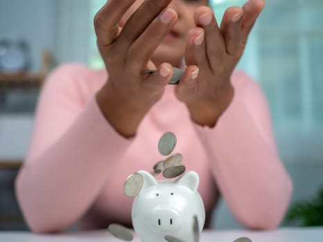 Woman wearing a pink shirt put coins in the piggy bank for saving money and financial concept, Business banking and financial concept, Saving money for retirement funds and insurance concept.