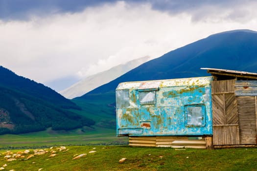 shabby mountain cabin made of old truck bed camper at summer day