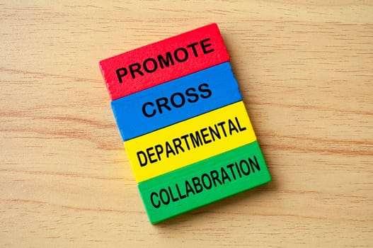 Top view of Promote Cross Departmental Collaboration text on multicolored wooden blocks. Business process improvement concept.