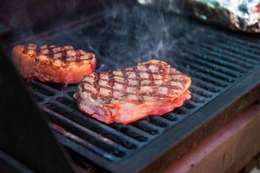Beef steaks with vegetables on the grill with flames