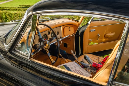 Lisbon, Portugal - Jan 20, 2024: Car design details, interior of vintage Jaguar car in full leather, authentic steering wheel with Jaguar logo and front panel. Newspaper in Portuguese on driver's seat.
