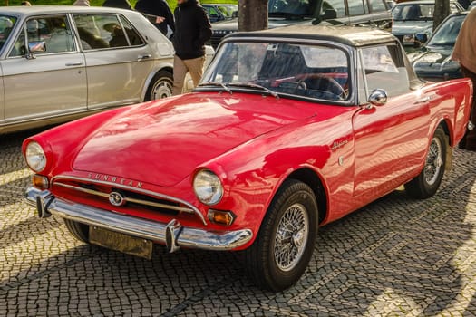 Lisbon, Portugal - Jan 20, 2024: Red Subeam Alpine Series IV vintage convertible sports car parked on cobblestone pavement road. Classice two-seater roadster or drophead coupe by Rootes Group, England, Great Britain