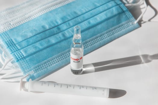 Coronavirus vaccine concept: covid-19 vaccine on the table with blue protective masks.