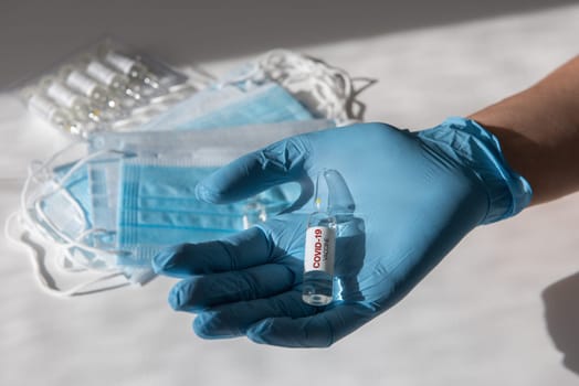 Coronavirus vaccine concept: covid-19 vaccine in doctor hand with blue protective gloves.