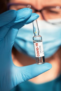 Coronavirus vaccine concept: covid-19 vaccine in doctor hand with blue protective gloves.