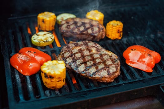 Beef steaks with vegetables on the grill with flames
