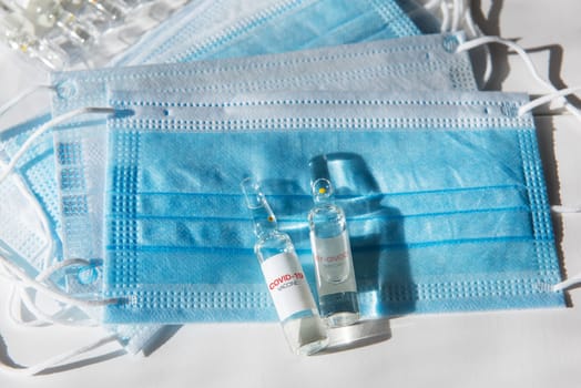 Coronavirus vaccine concept: covid-19 vaccine on the table with blue protective masks.