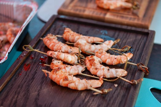 A professional cook prepares shrimps on the grill outdoor, food or catering concept