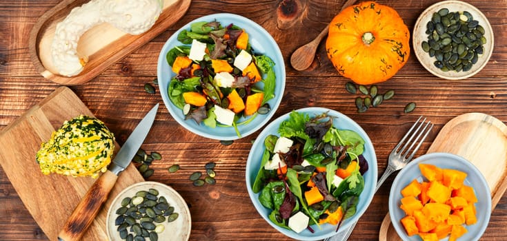 Fresh vegetable salad with autumn Hokkaido pumpkin, feta cheese and greens. Healthy vegan.