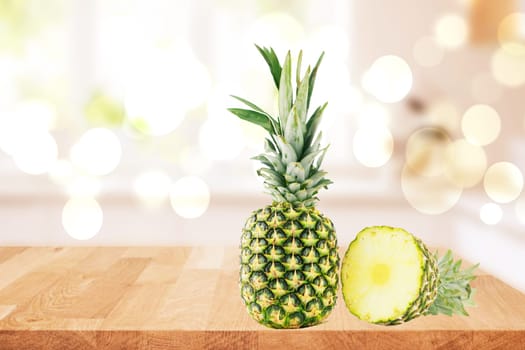 Fresh ripe pineapple fruits on a table over a abstract blurred bright natural windows background. Healthy nutrition. Tropical fruits or healthcare concept. Space for design.