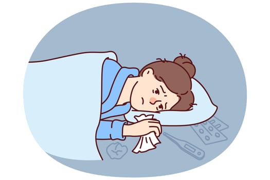 Woman sick with flu lies under blanket with handkerchief in hand near thermometer and medicines to treat fever. Sick girl needs qualified medical care due to outbreak of viral infection