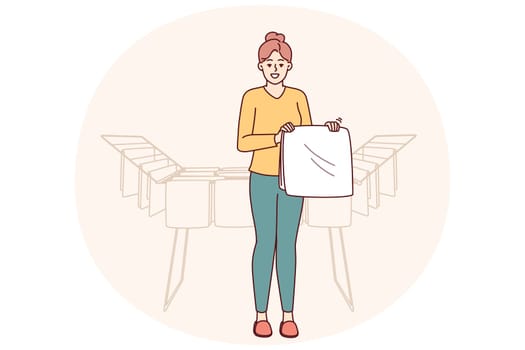 Woman housewife stands near dryer with clean towels doing household chores to create comfort in apartment. Housewife girl with washed item for advertising washing powder or aromatic laundry gel