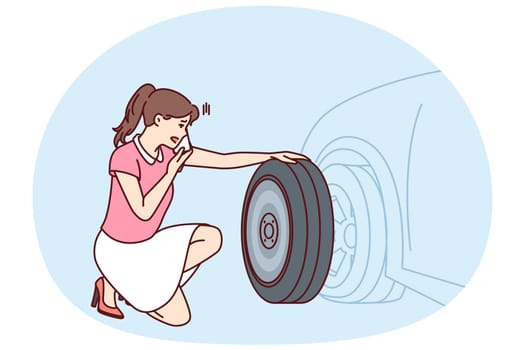 Woman looks at punctured car tire trying to call for help to change tire or haul automobile to garage. Girl near car parked on roadside needs emergency help for concept of breakdown on road