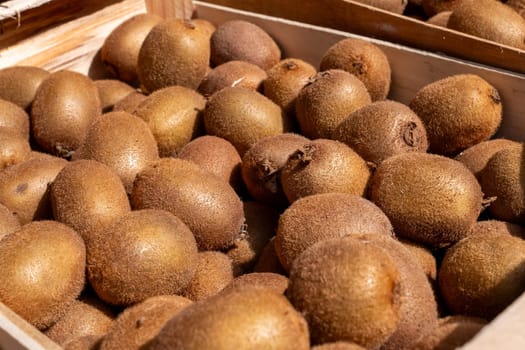 A crate full of brown kiwi fruit. The fruit is ripe and ready to eat. The crate is wooden and has a rustic feel to it