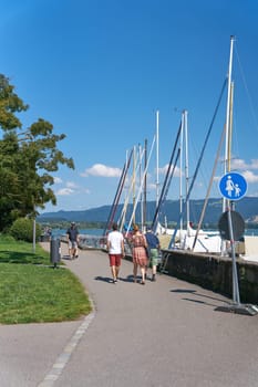 Walkers on a lakeside path in Lindau on Bodensee, Lake Constance in Germany