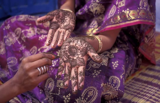 a Rajasthani women is making a Henna Hand painting in the Town of Jaisalmer in the Province of Rajasthan in India.  India, Jaisalmer, January, 1998