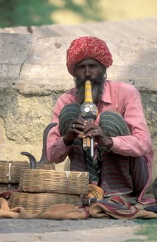 a snake charmer play music in front of cobra snake in the city of Jaisalmer in the Province of Rajasthan in India.  India, Jaisalmer, January, 1998