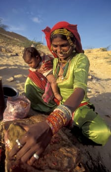 a Rajasthani women is cocking on a fire with her Baby in the Town of Jaisalmer in the Province of Rajasthan in India.  India, Jaisalmer, January, 1998