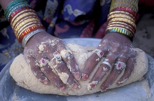 a Rajasthani women is cocking and bake a bread on a fire with her Baby in the Town of Jaisalmer in the Province of Rajasthan in India.  India, Jaisalmer, January, 1998