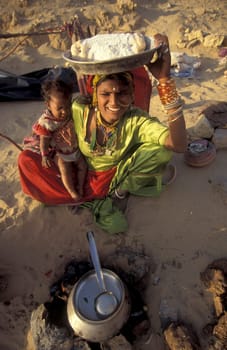 a Rajasthani women is cocking on a fire with her Baby in the Town of Jaisalmer in the Province of Rajasthan in India.  India, Jaisalmer, January, 1998
