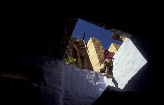 a women sits on her balcony in the old Town in the Jaisalmer Fort with the city of Jaisalmer in the Province of Rajasthan in India.  India, Jaisalmer, January, 1998