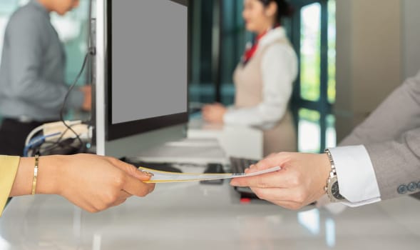 Airport check in. Hand of female traveler receive boarding pass ticket from customer check in male officer at airline service counter
