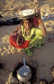 a Rajasthani women is cocking on a fire with her Baby in the Town of Jaisalmer in the Province of Rajasthan in India.  India, Jaisalmer, January, 1998