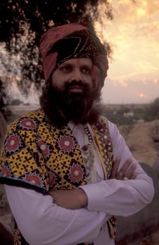 a camel herder in traditional Rajasthani dress at the Bikaner Camel Festival in the Town of Bikaner in the Province of Rajasthan in India.  India, Bikaner, January, 1998