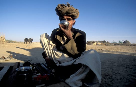 a Rajasthani Men drinks a Tea in a small Village near the Town of Bikaner in the Province of Rajasthan in India.  India, Bikaner, January, 1998