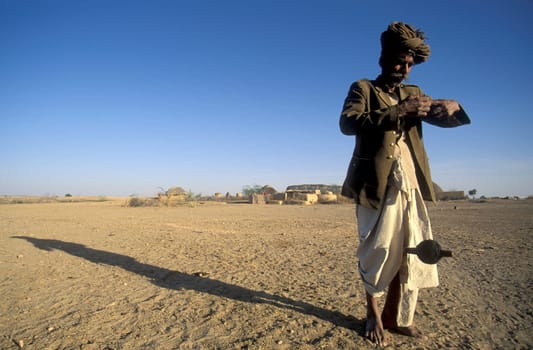 A old Men work with a Cord Spindle in a small Village near the Town of Bikaner in the Desert Thar in the Province of Rajasthan in India.  India, Bikaner, January, 1998