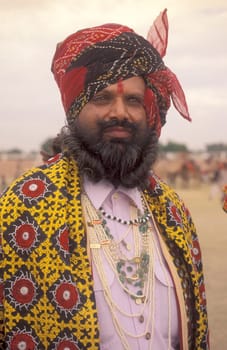 a camel herder in traditional Rajasthani dress at the Bikaner Camel Festival in the Town of Bikaner in the Province of Rajasthan in India.  India, Bikaner, January, 1998
