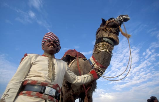 a camel herder in traditional Rajasthani dress at the Bikaner Camel Festival in the Town of Bikaner in the Province of Rajasthan in India.  India, Bikaner, January, 1998