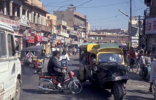 a Motorbike and Tuk Tuk Taxi traffic on a road in the City of Jaipur in the Province of Rajasthan in India.  India, Jaipur, January, 1998