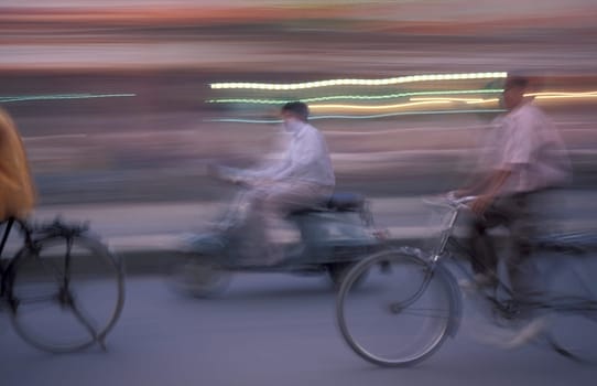a Motorbike and bicycle traffic on a road in the City of Jaipur in the Province of Rajasthan in India.  India, Jaipur, January, 1998