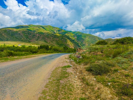 empty road to mountains at sunny summer day in Kyrgyzstan