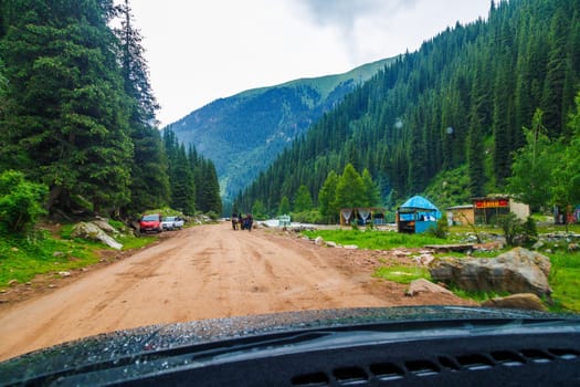 yurt camp and merchandise in spruce forest covered mountain slopes at rainy summer day in Grigoryevskoye Gorge in Kyrgyzstan - July 5, 2023
