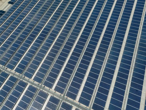 Solar energy for factory and warehouse building. Solar panels on roof of industrial plant. Commercial solar power. Rooftop solar power. Rooftop renewable energy system. Sustainable green energy.