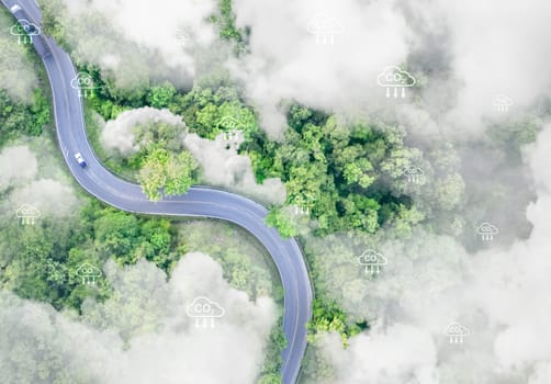 Sustainable transport and natural carbon sink. Aerial view of electric vehicles on highway through lush green forest. Zero-emission mobility and environmental conservation for reduced carbon emissions