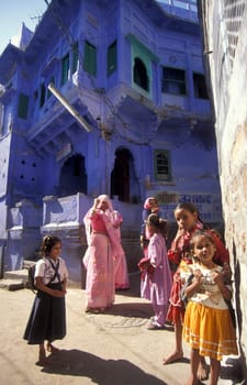 people in front of a blue painted living House in the Blue City and Town of Jodhpur in the Province of Rajasthan in India.  India, Jodhpur, January, 1998