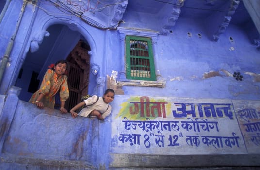 Children at a blue painted living House in the Blue City and Town of Jodhpur in the Province of Rajasthan in India.  India, Jodhpur, January, 1998