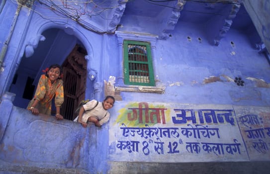 Children at a blue painted living House in the Blue City and Town of Jodhpur in the Province of Rajasthan in India.  India, Jodhpur, January, 1998