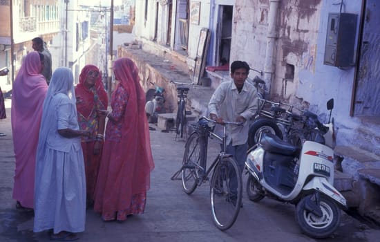 People in a alley with blue painted living House in the Blue City and Town of Jodhpur in the Province of Rajasthan in India.  India, Jodhpur, January, 1998