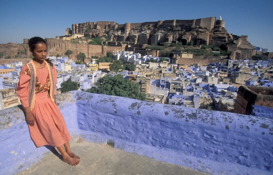 a Women on her Roof Top a view of the Meherangarh in the Town and Blue City of Jodhpur in the Province of Rajasthan in India.  India, Jodhpur, January, 1998