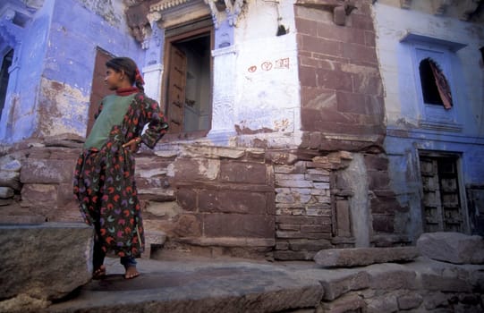 a girl at a blue painted living House in the Blue City and Town of Jodhpur in the Province of Rajasthan in India.  India, Jodhpur, January, 1998