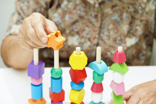 Asian elderly woman playing puzzles game for treatment dementia prevention and Alzheimer disease.