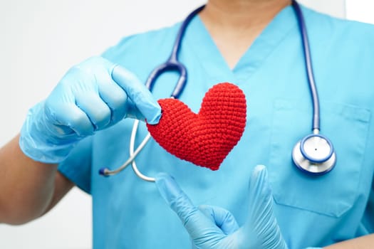 Asian woman doctor holding red heart for health in hospital.