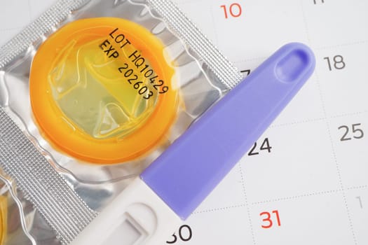 Pregnancy test and condom for female on calendar, ovulation day.